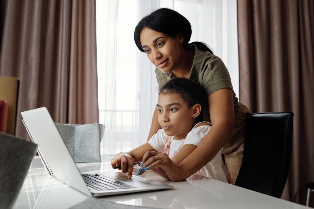 Mãe e filha estudando com tecnologia em casa